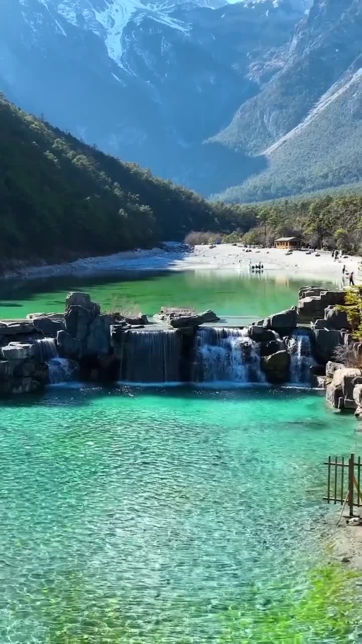 在玉龙雪山脚下，我看到了美丽的风景。周围的山的云，它是如此美丽！云层里的山白得像奶油。山下的树很壮。附近的草是黄色的，只有少数是绿色的。#玉龙雪山